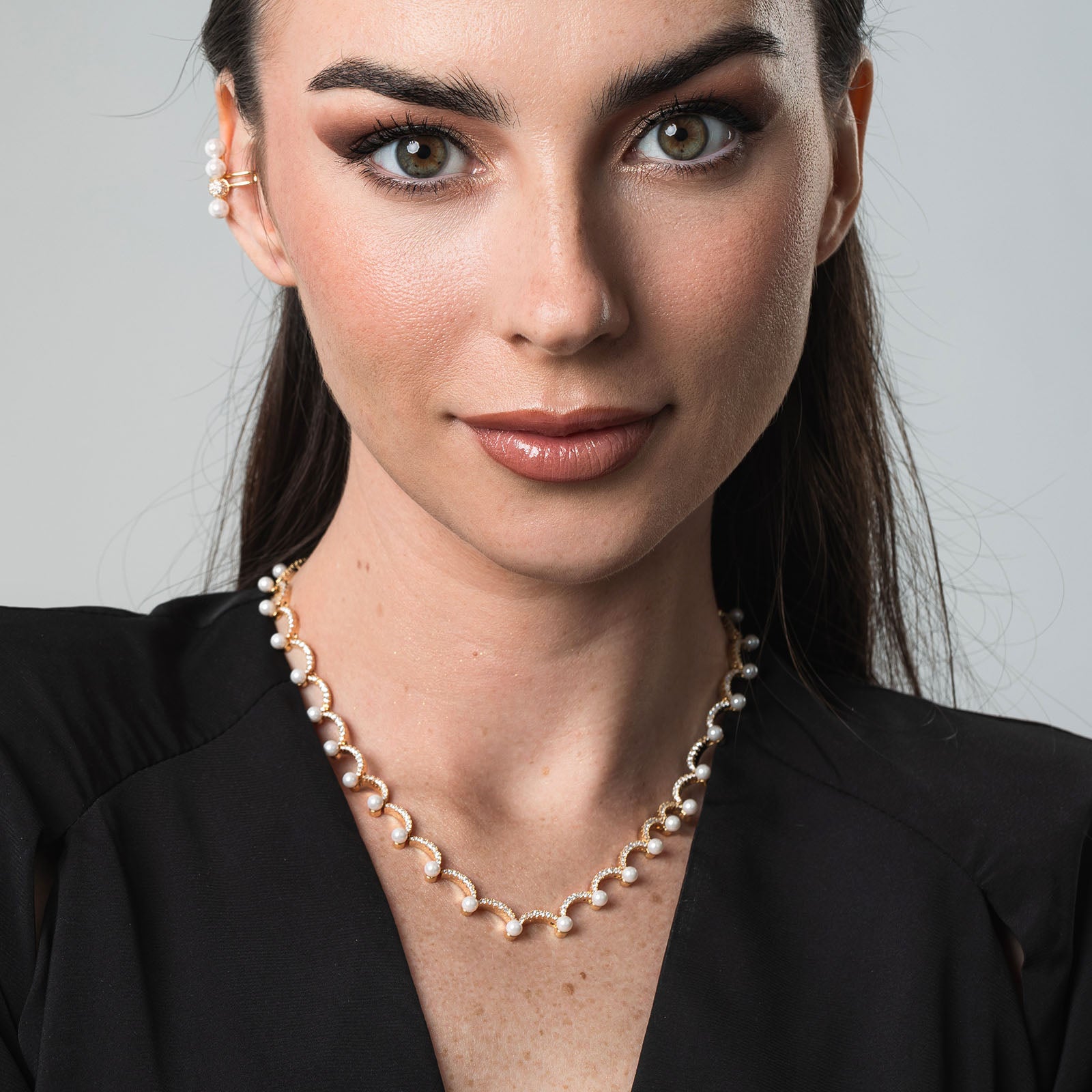 Woman wearing a pearl necklace against a neutral background