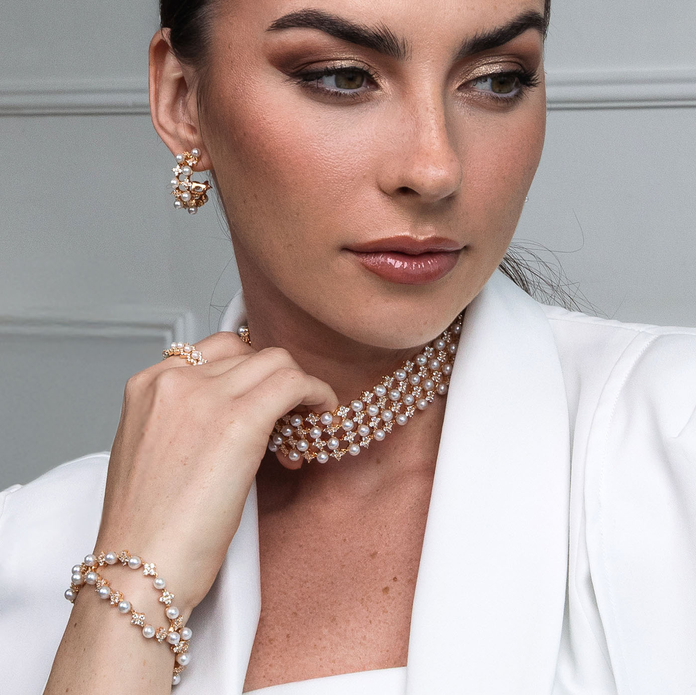 Woman wearing a pearl necklace and bracelet against a neutral background