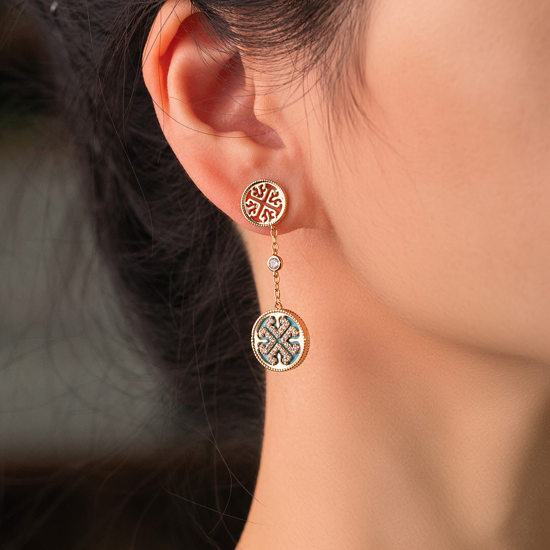 A person wearing gold-plated spherical earrings with zircon stones.