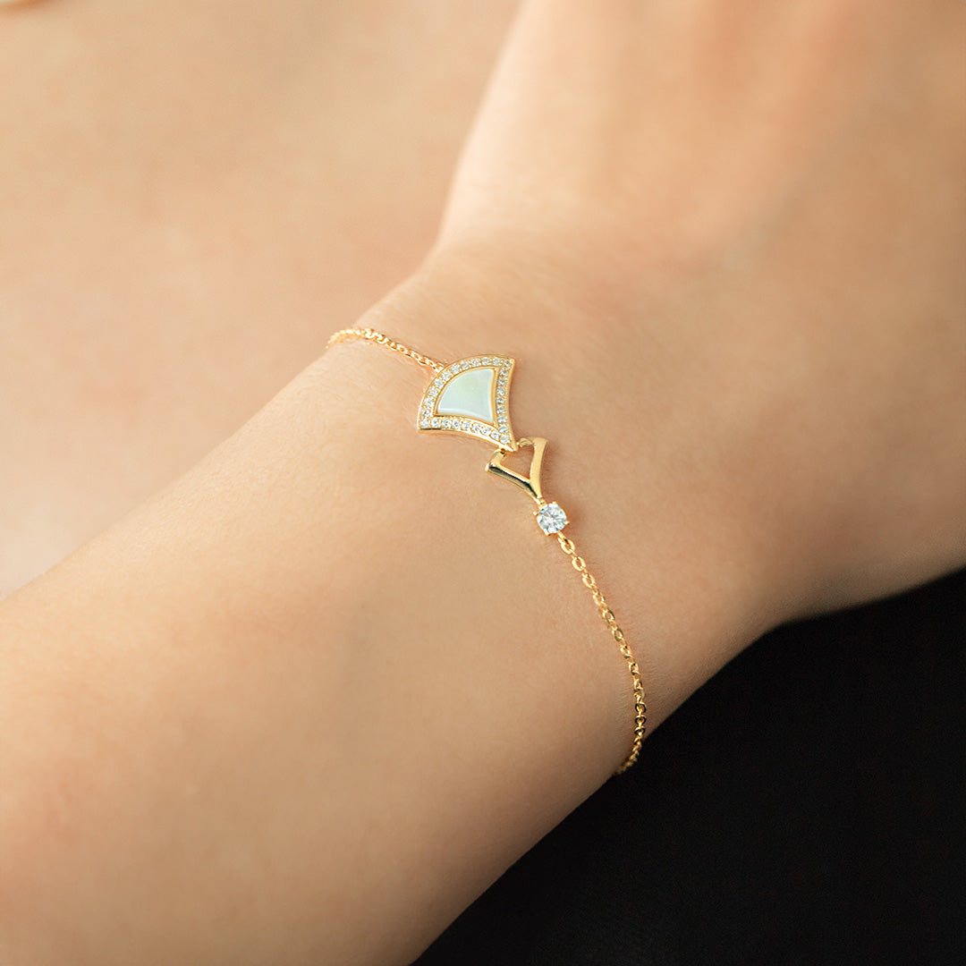 A gold-plated sterling silver bracelet with a geometric design featuring a diamond-like stone and a chain link, worn on a person's wrist.