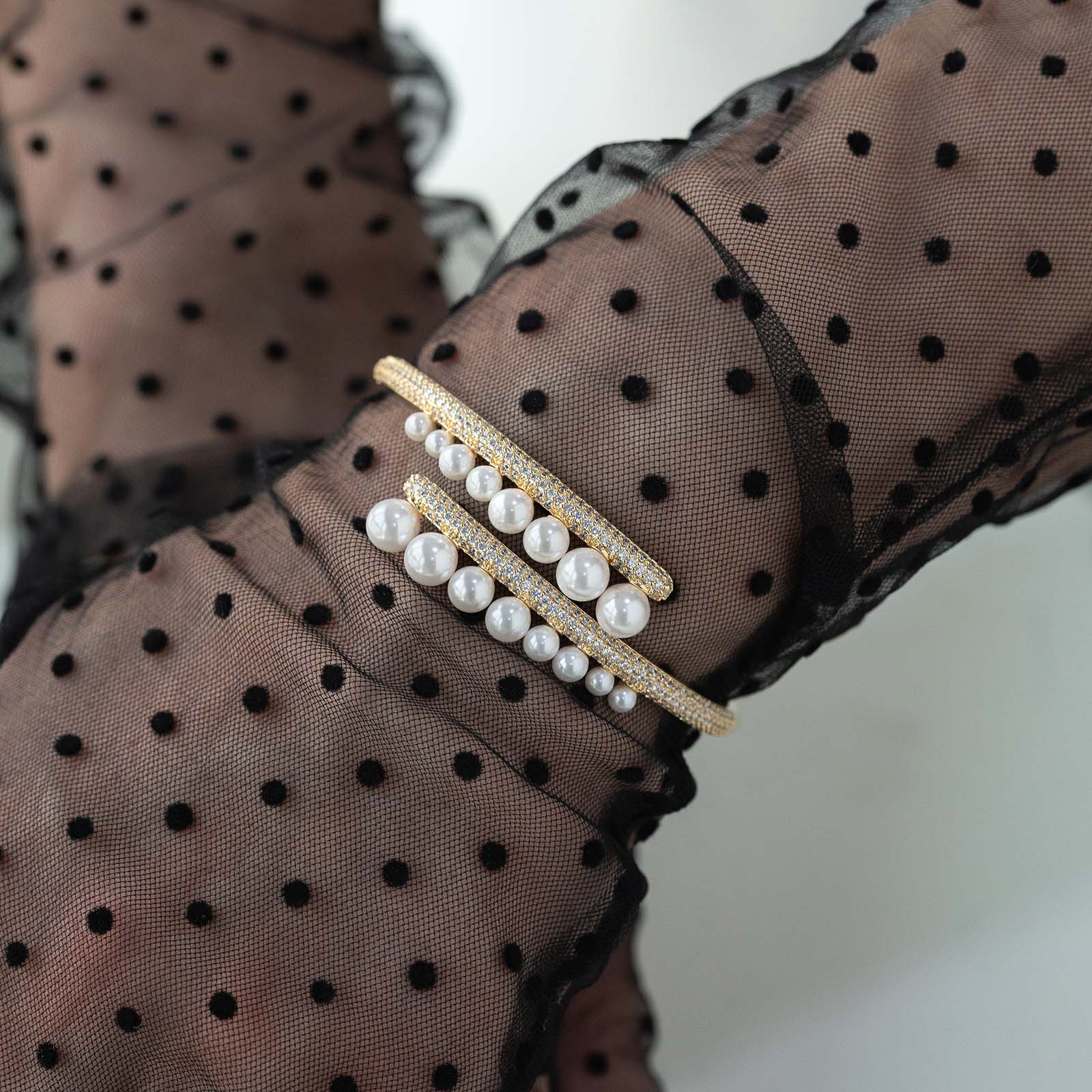 Pearl bracelet on a black polka dot fabric background