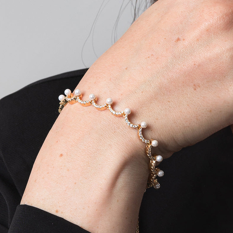 Pearl bracelet on a person's wrist against a neutral background