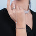 Close-up of a hand wearing multiple diamond jewelry pieces including a bracelet, ring, and necklace.