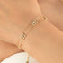 Gold bracelet with star-shaped charms on a wrist against a neutral background