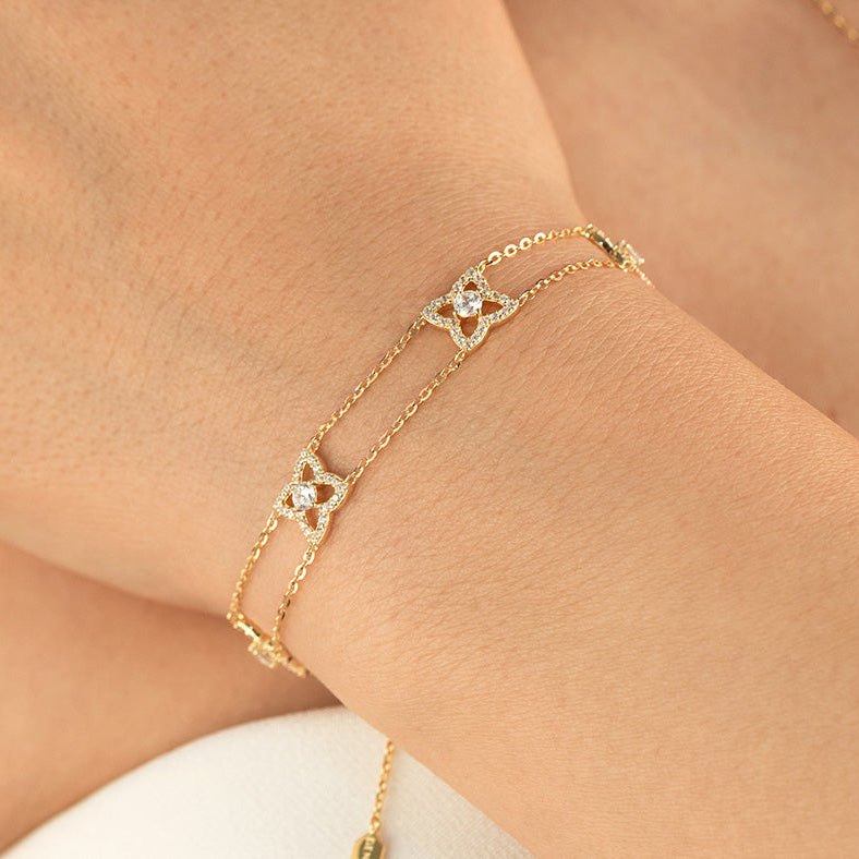 Gold bracelet with star-shaped charms on a wrist against a neutral background