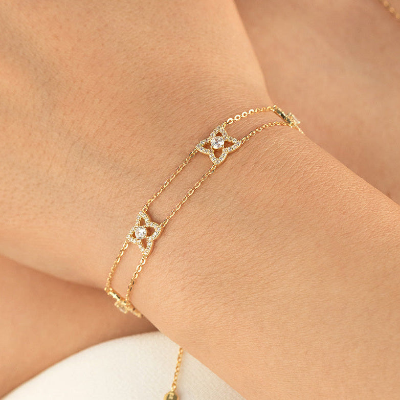 Gold bracelet with diamond accents on a wrist against a neutral background