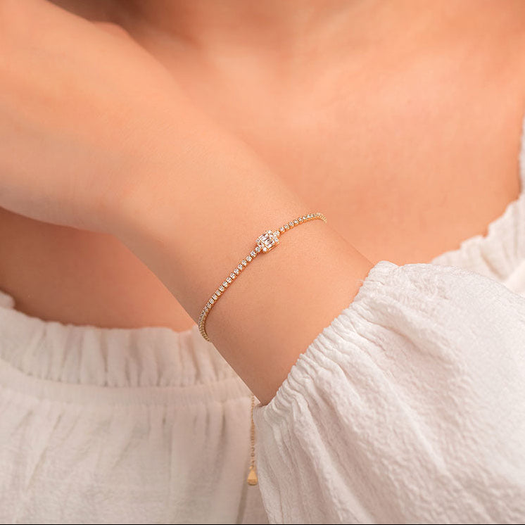 A person wearing a sterling silver bracelet with 18K gold plating and zircon stones on their wrist.