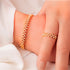 A set of gold-plated bangle bracelets with pearl embellishments, displayed on a person's wrist.