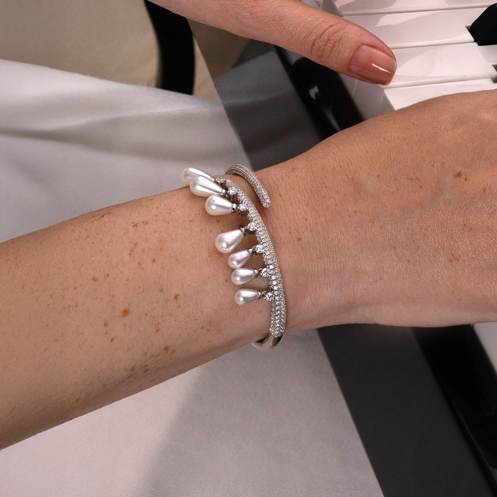 Close-up of a wrist wearing two pearl bracelets on a neutral background