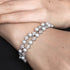 Pearl bracelet with silver accents on a wrist against a neutral background