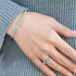 Hand wearing a bracelet and ring with turquoise stones on a gray textured background