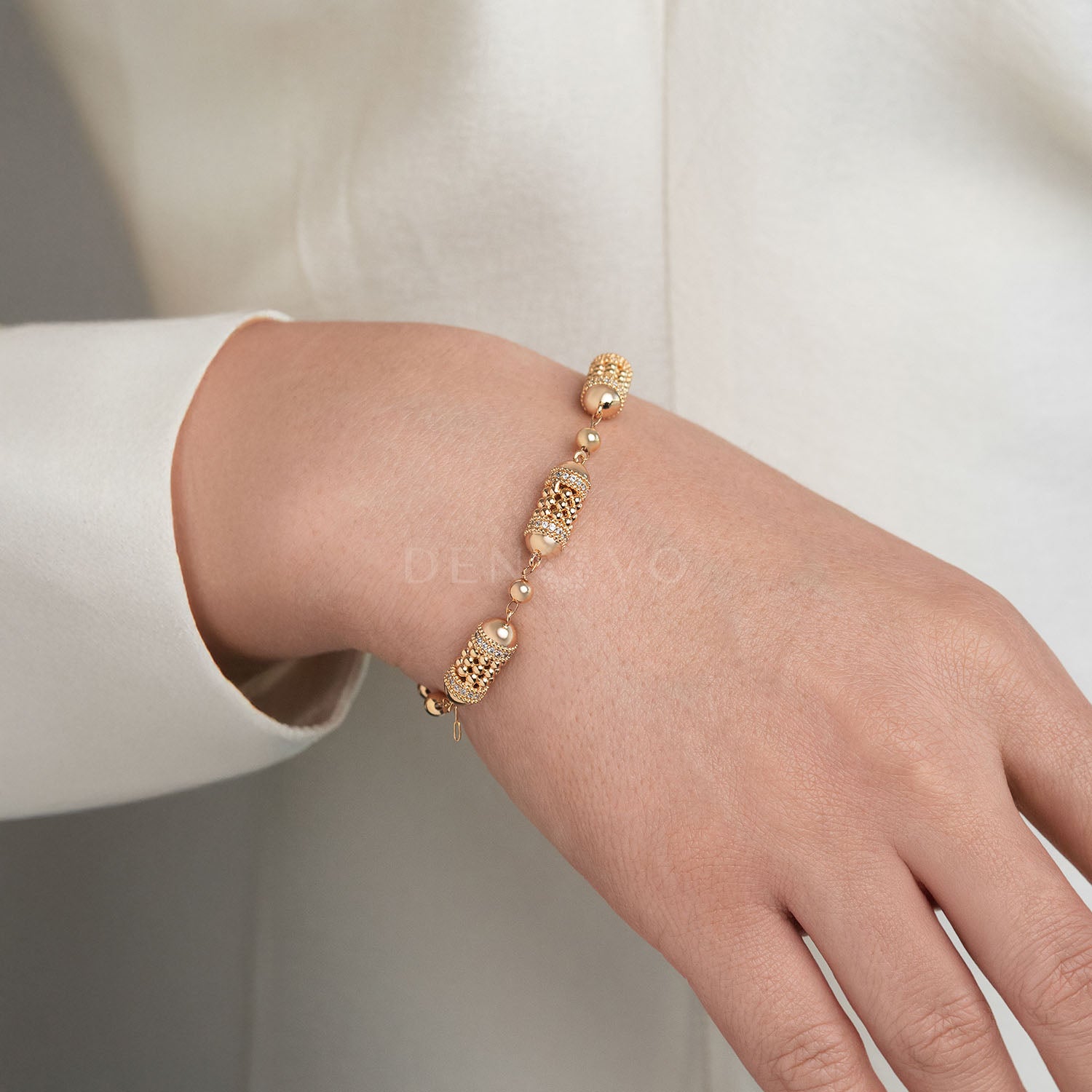 Gold bracelet on a person's wrist with a neutral background