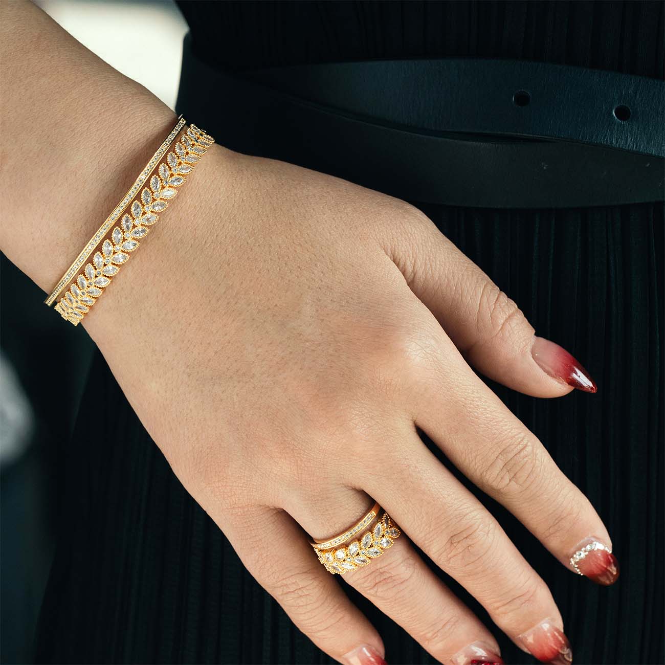 A gold-plated bangle set with a leafy halo design, worn on a person's wrist.