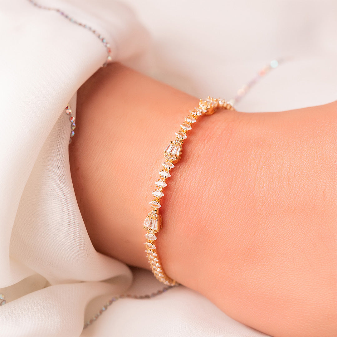 A gold-plated bracelet with zircon stones resting on a person's wrist, showcasing its elegant design.