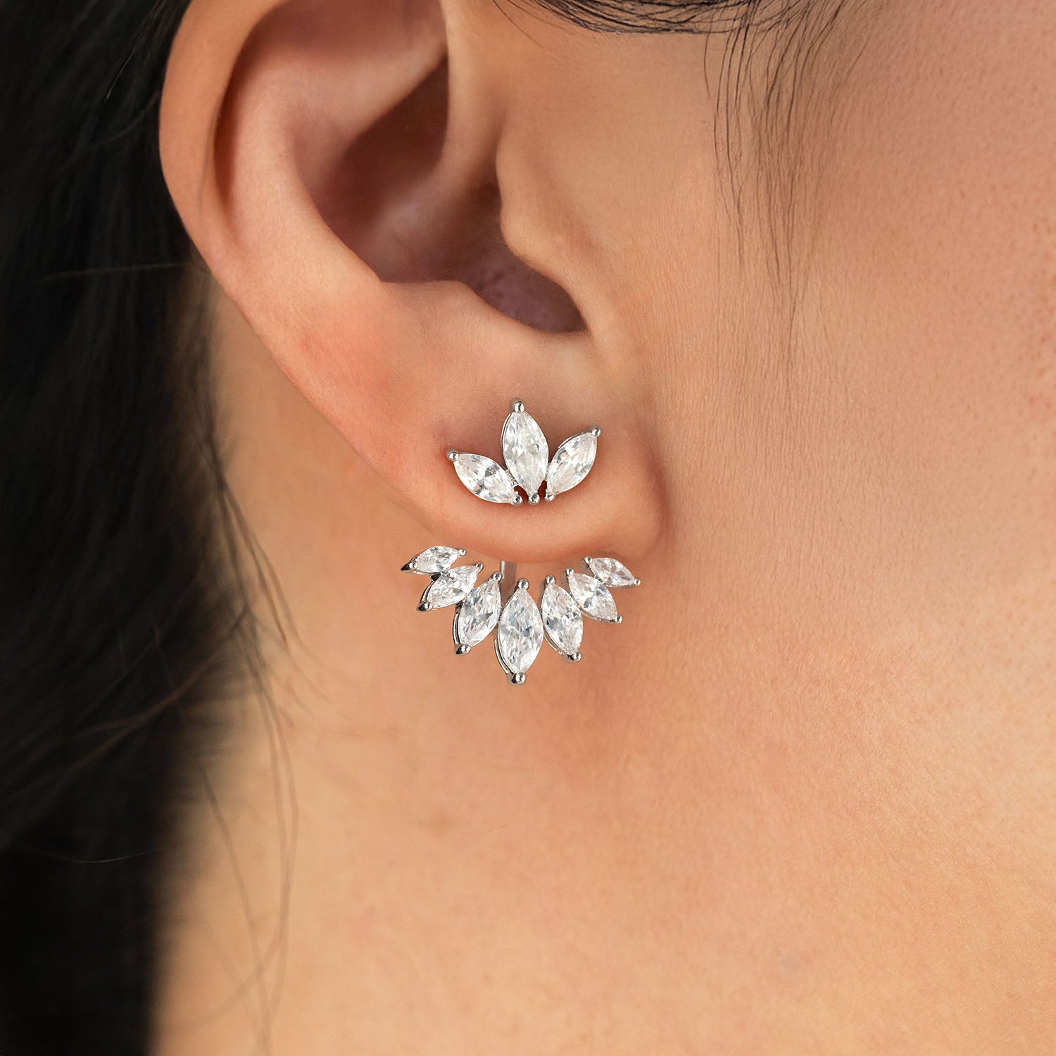 Close-up of a person wearing a pair of diamond earrings.