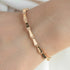 Rose gold bracelet with diamond accents on a wrist against a neutral background