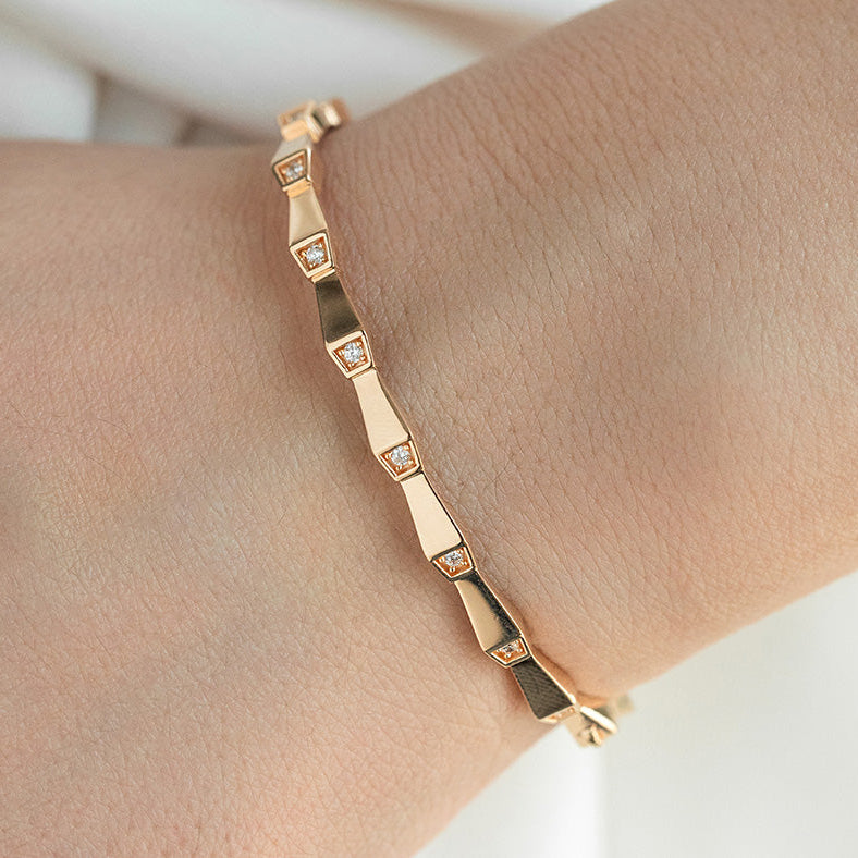 Rose gold bracelet with diamond accents on a wrist against a neutral background