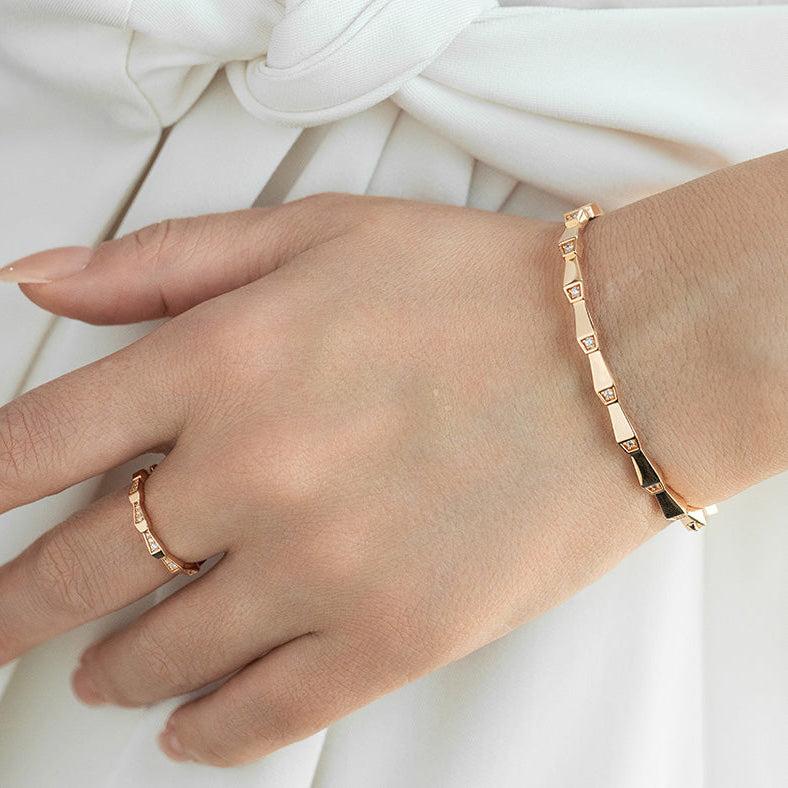 Rose gold bracelet and ring on a hand against a white background