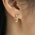Gold hoop earring with small diamonds worn by a person