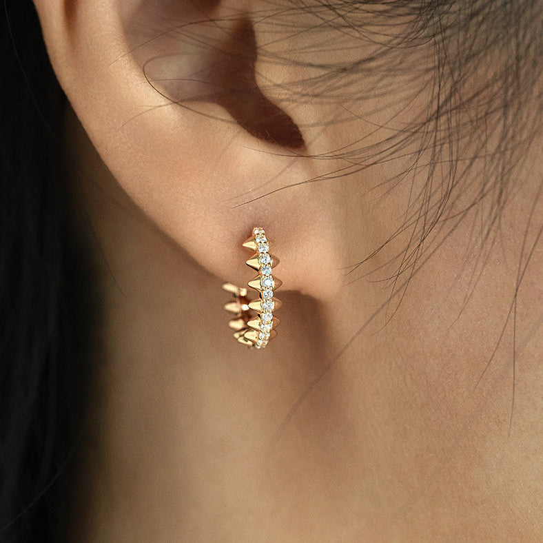Gold hoop earring with small diamonds worn by a person