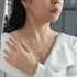 Woman wearing a gold necklace, ring, and bracelet with a blurred background