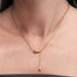 Gold necklace with a unique pendant on a person's neck