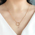 Gold necklace with a circular pendant on a person wearing a white top