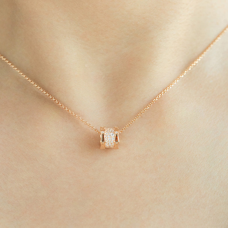 Gold necklace with a square pendant on a beige background