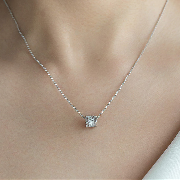 Silver necklace with a small pendant on a person's neck