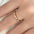Rose gold ring on a person's finger against a neutral background