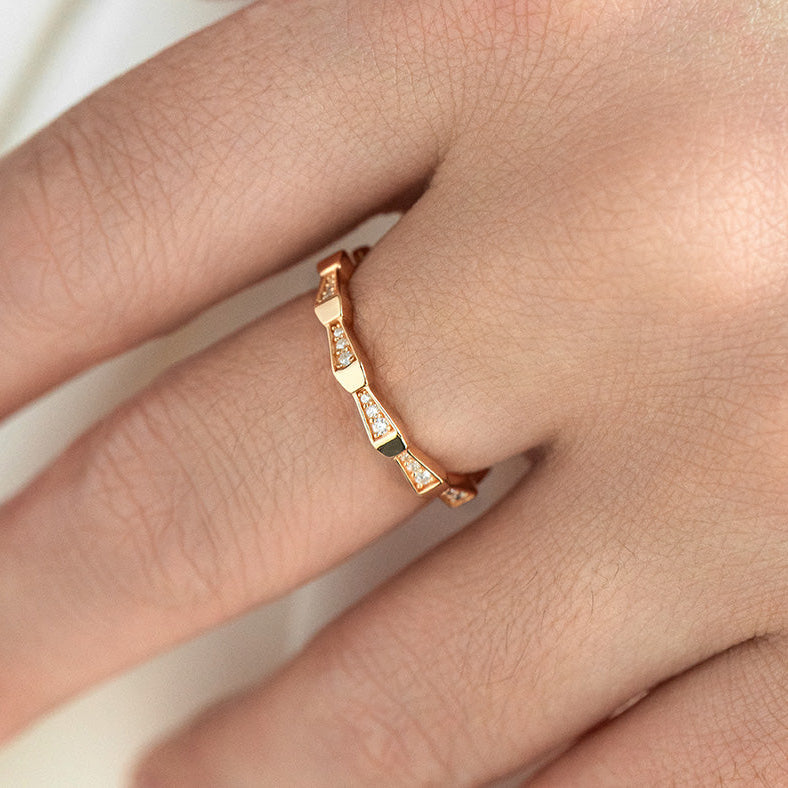 Rose gold ring on a person's finger against a neutral background