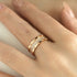 Rose gold ring with diamonds on a finger against a neutral background