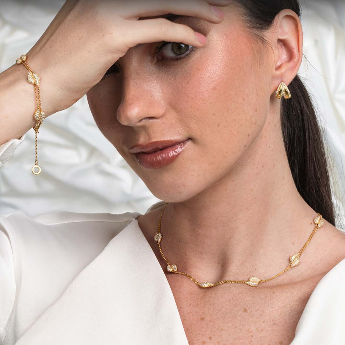 Woman wearing gold jewelry against a neutral background