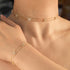 Gold anklets with diamond-like stones on a person's wrist and ankle.
