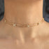 Gold anklet with small square charms on a person's ankle against a neutral background