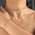Silver necklace and bracelet set on a person's neck and wrist against a neutral background
