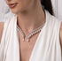 Close-up of a woman wearing a delicate silver necklace with teardrop pendants against a neutral background.