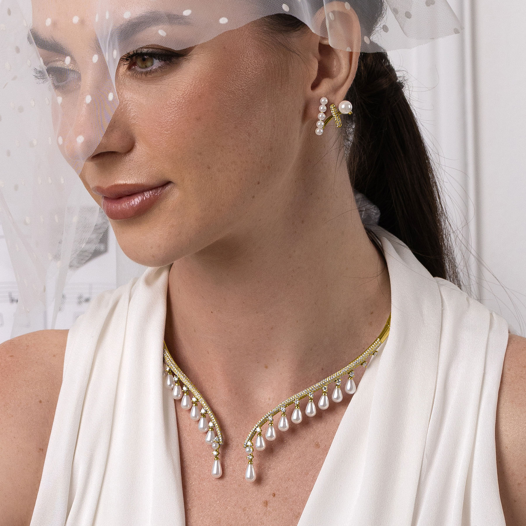Woman wearing a pearl necklace and earrings with a white veil