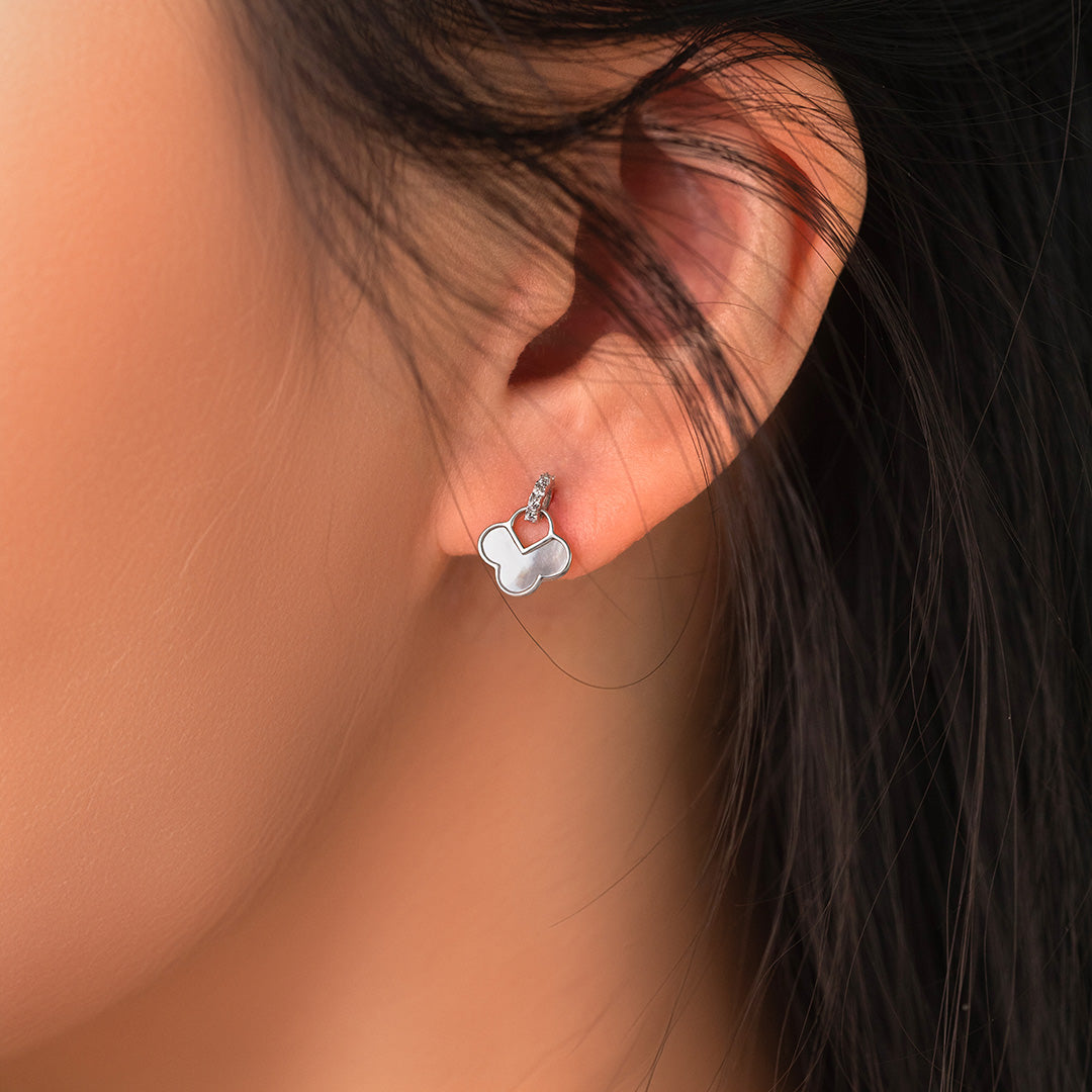 A close-up image of a woman's ear wearing a silver and gold-plated earring with a cloud design and a small pearl stone.