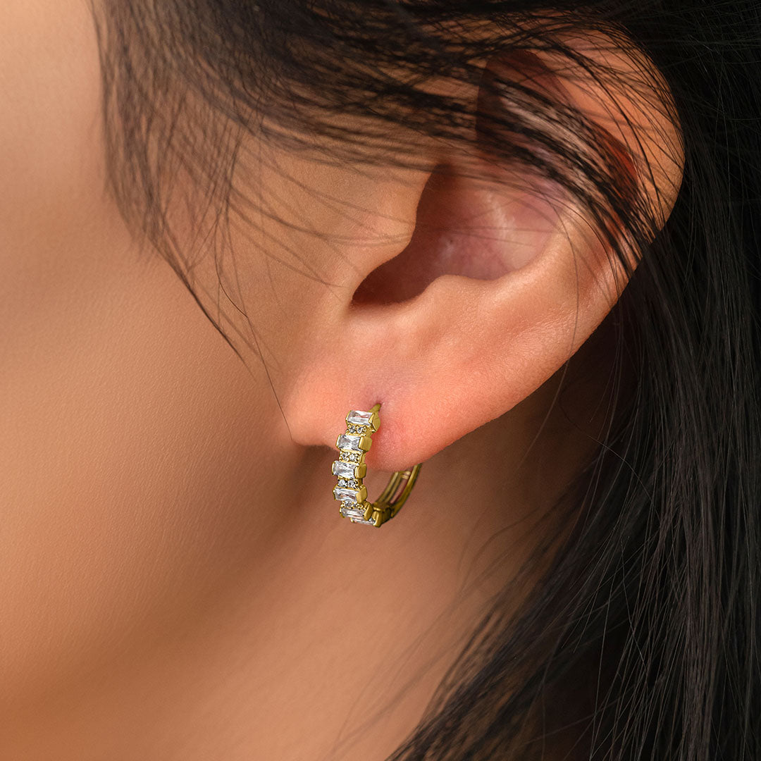 A close-up image of a woman's ear wearing a gold-plated sterling silver earring with zircon stones.