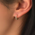 A close-up image of a woman's ear wearing a sterling silver and 18K gold plated earring with a zircon stone.