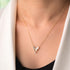 A person wearing a white blazer and a black top is showcasing a sterling silver necklace with a gold plating, featuring a butterfly pendant and small zircon stones.