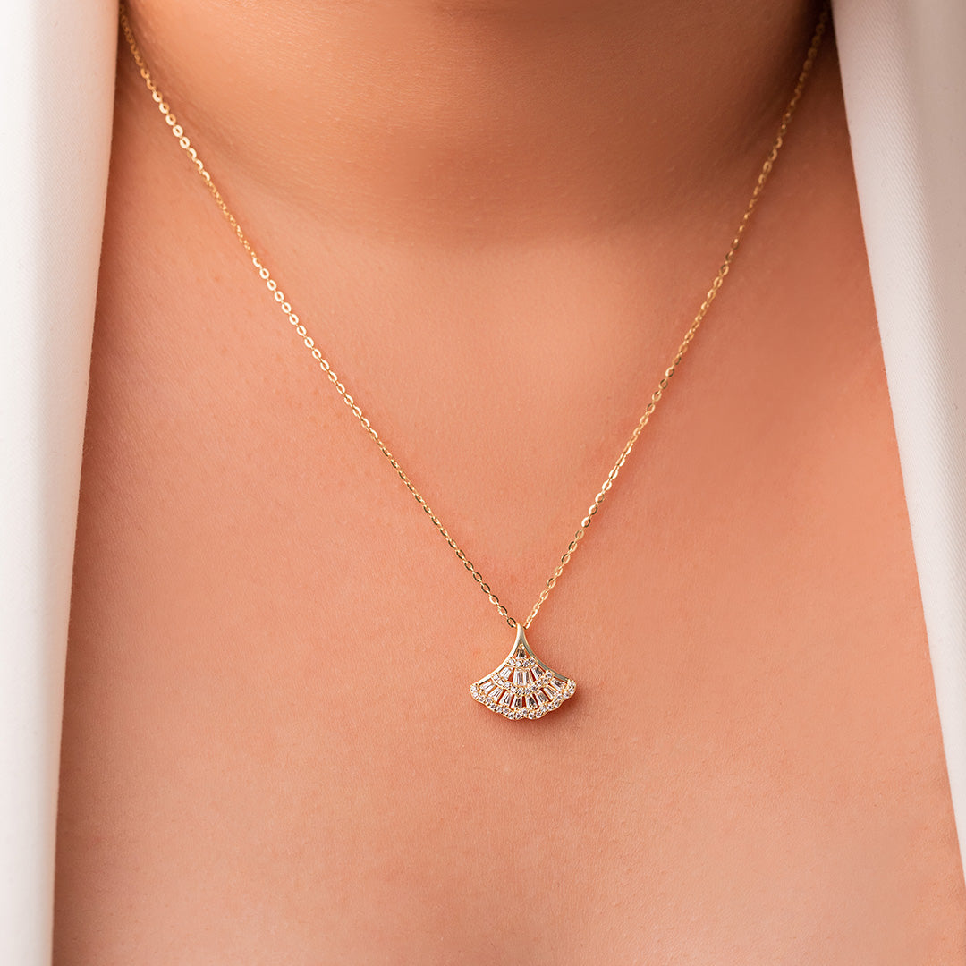 A close-up image of a person wearing a gold-plated sterling silver necklace with a geometric-patterned pendant.