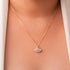 A close-up image of a person wearing a gold-plated sterling silver necklace with a geometric-patterned pendant.