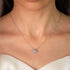 A close-up image of a sterling silver necklace, featuring a central zircon stone, presented on a model wearing a white bridal gown.