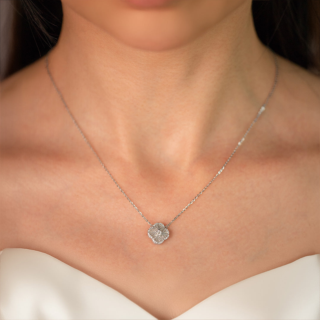 A close-up image of a sterling silver necklace, featuring a central zircon stone, presented on a model wearing a white bridal gown.