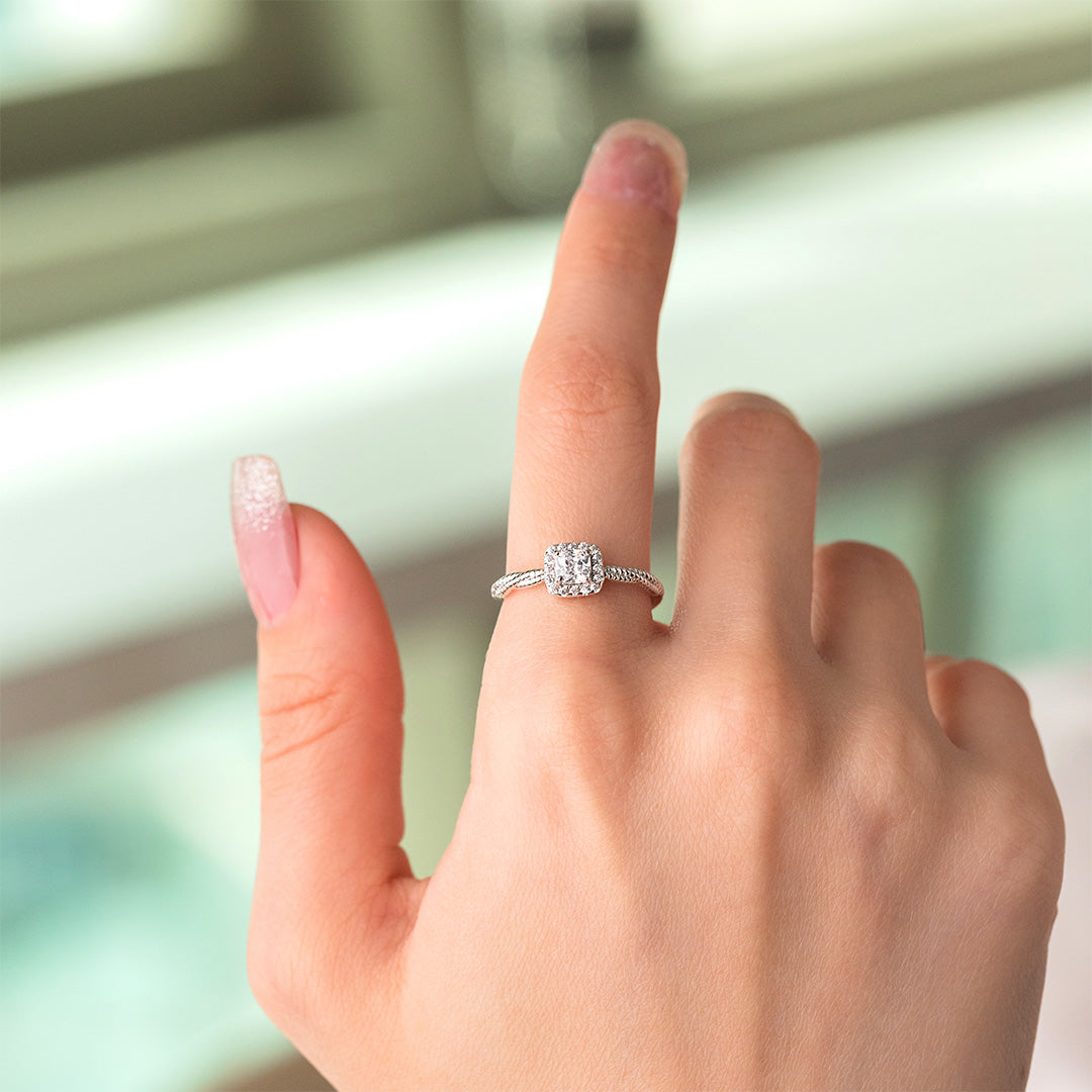 A person's hand displaying a twisted radiance ring with zircon stones set in gold plating on a sterling silver band.