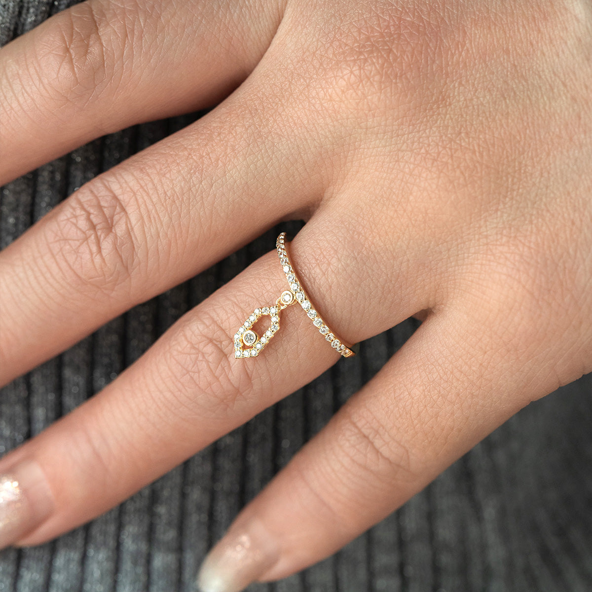 Close-up of a hand wearing a rose gold ring with diamonds on a textured gray background