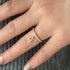Close-up of a hand wearing a rose gold ring with diamonds on a textured gray background