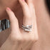 Close-up of a hand wearing multiple pearl and silver rings on a neutral background